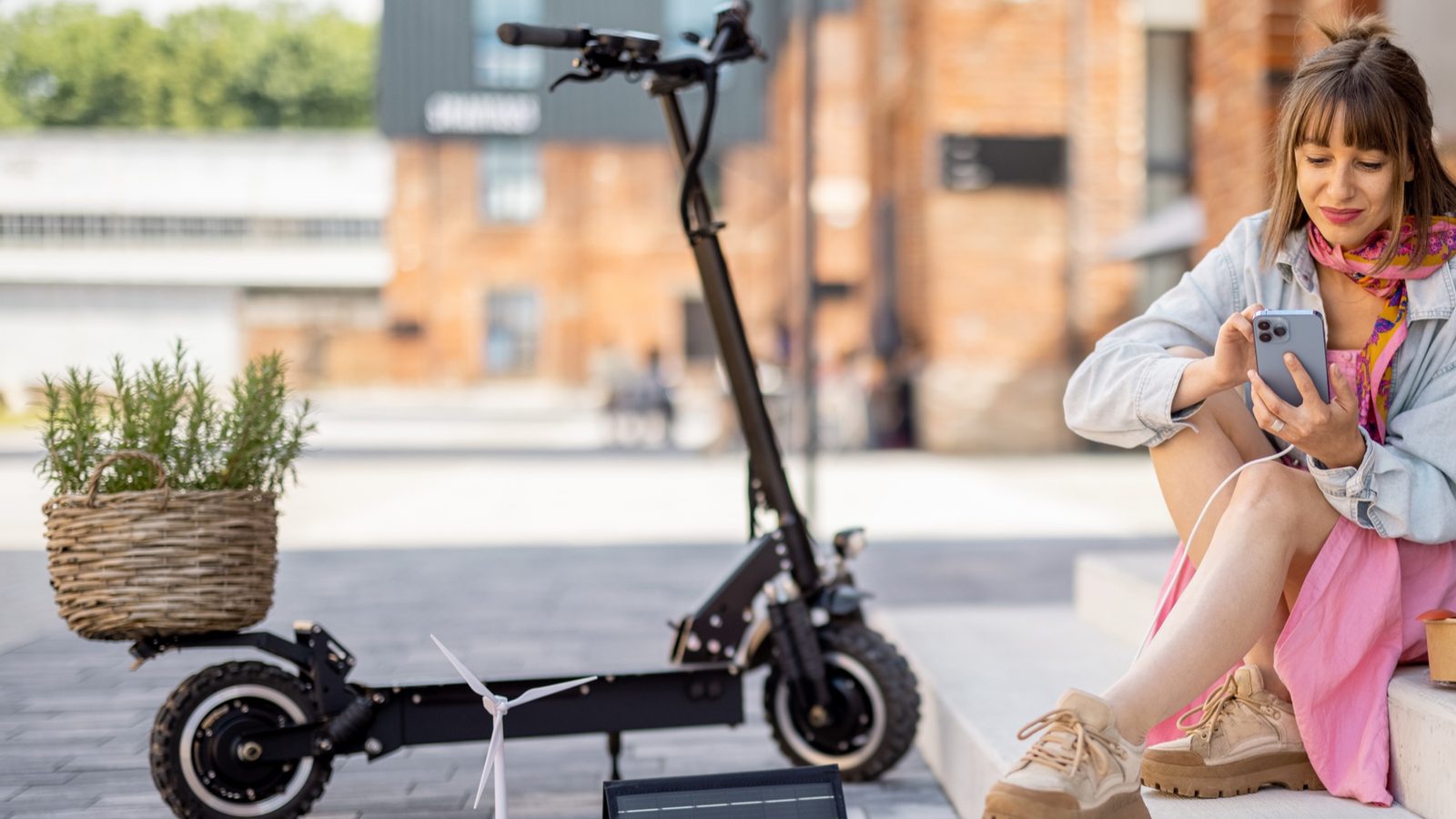 Electric scooter parked on a city footpath beside a rider sitting on the steps