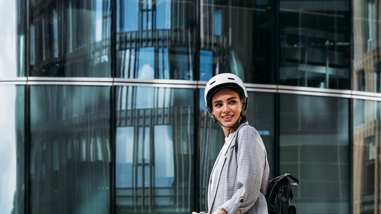Woman wearing a helmet riding an electric scooter in an urban environment